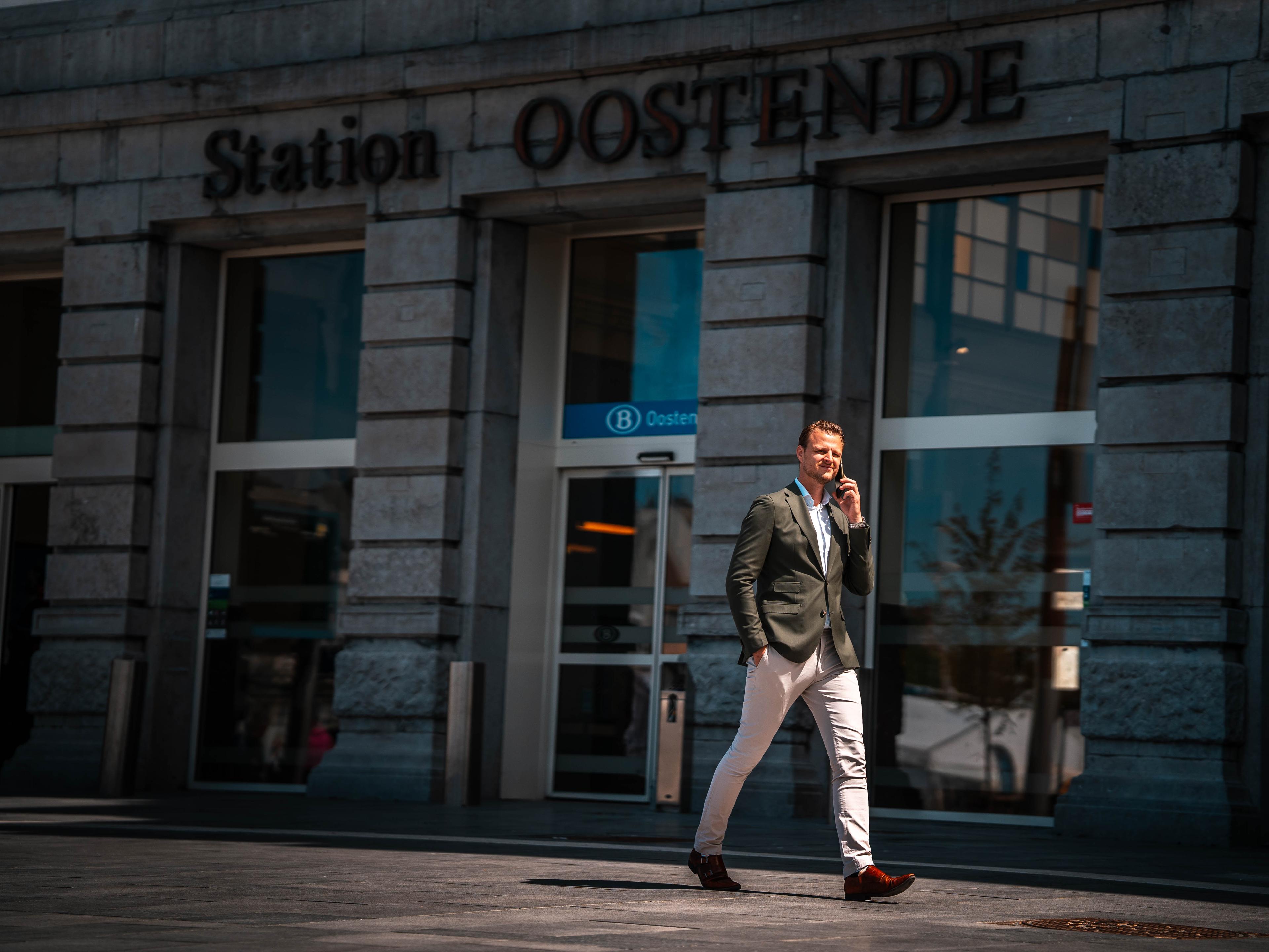 Zaakvoerder met gsm in hand voor station Oostende.